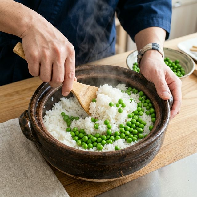 炊き上がった白米に、鮮やかな緑色のまま茹で上げた豆を後から混ぜ合わせている様子。シワを防ぐための重要なプロのテクニックを解説。